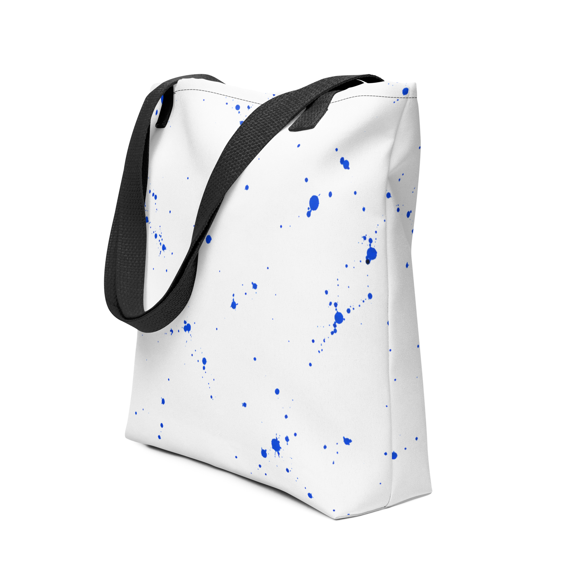 White tote bag with cobalt blue ink splatter and black straps on a clean background